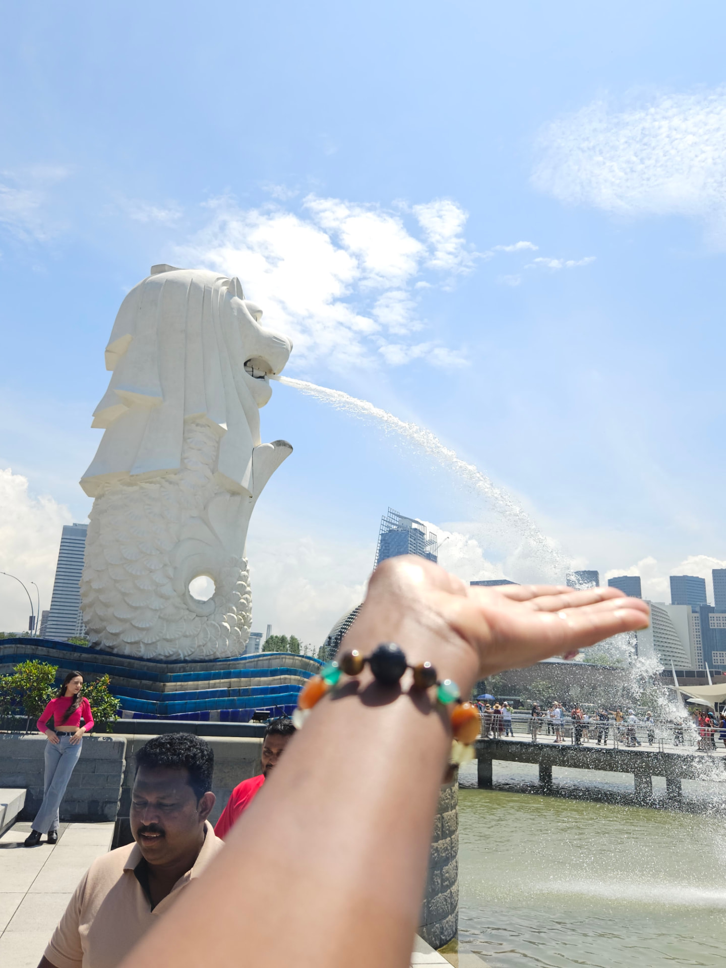 A traveller reaching towards the Merlion fountain in Singapore